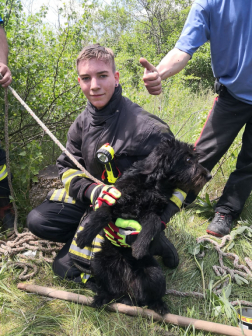 A fiatal önkéntes tűzoltó boldogan öleli a kimentett kutyát
